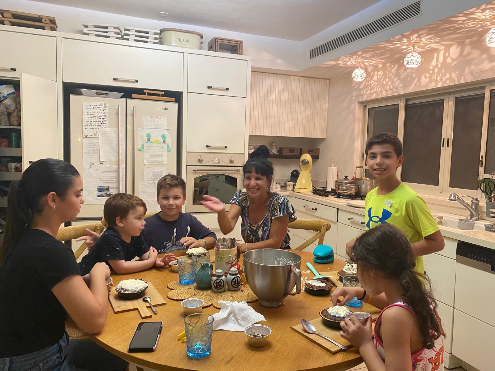 רותי סביב שולחן המטבח עם קבוצת ילדים בסדנה