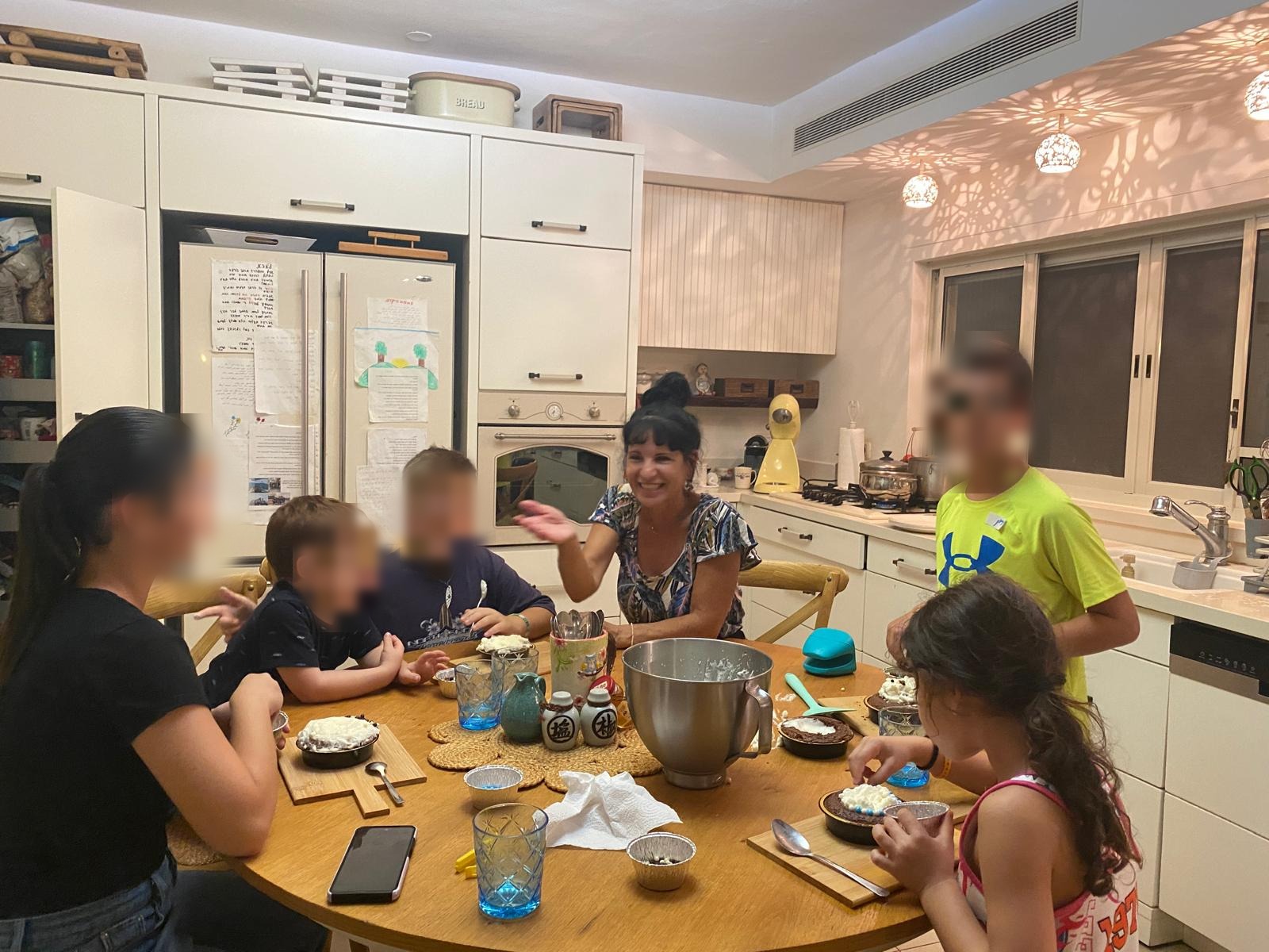אני סביב שולחן המטבח עם קבוצת ילדים בסדנה