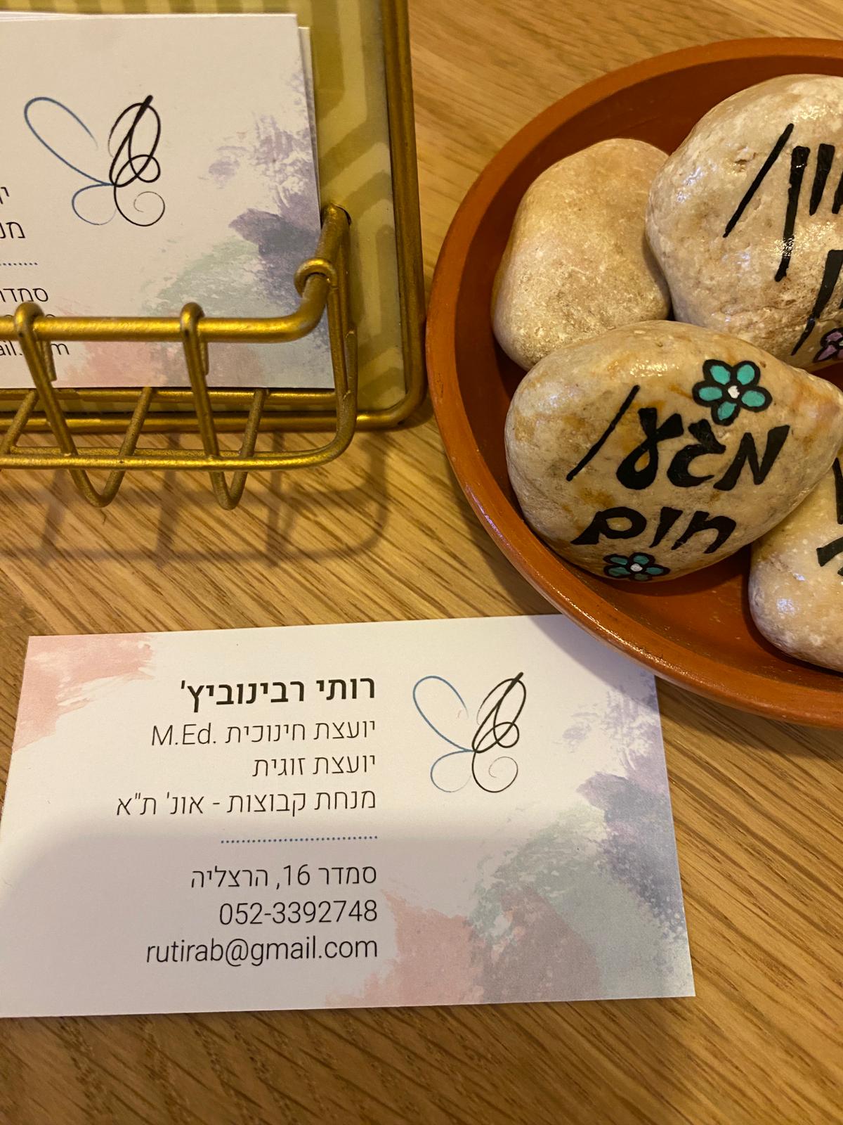 כרטיס הביקור של רותי לצד אבנים עם המילים ׳קשר׳ ו׳מקום׳